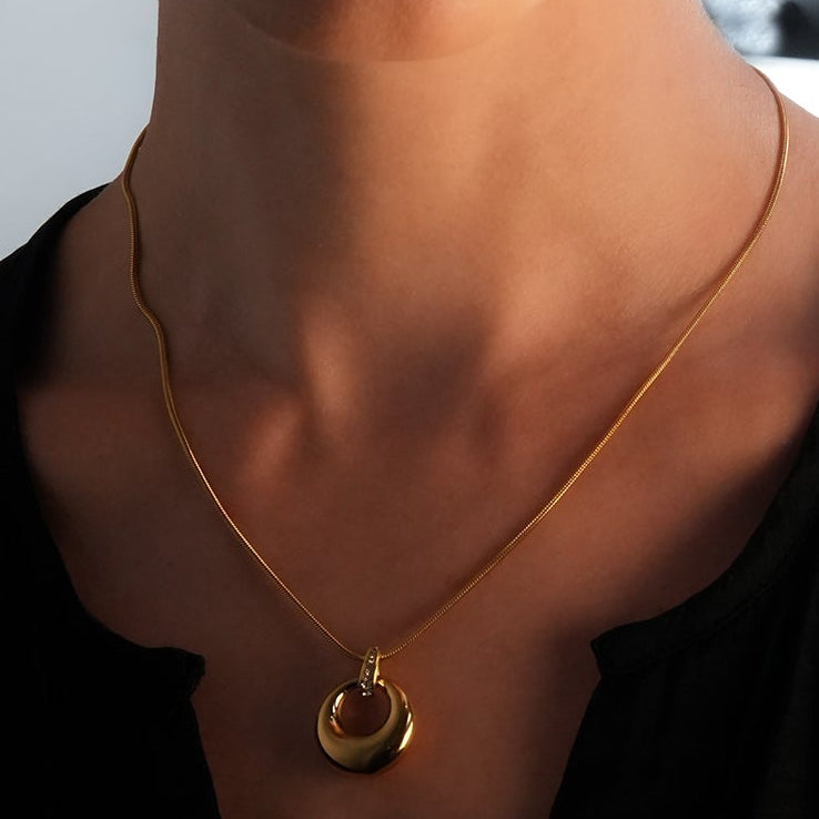 ALBASIMI : Chaîne peau de serpent avec fermoir serti d'oxydes de zirconium (CZ) et pendentif cercle asymétrique.